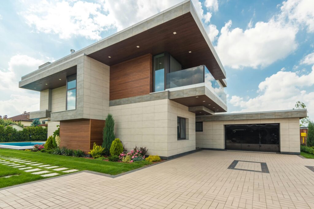 Contemporary luxury house with a sleek design, lush garden, and blue sky.