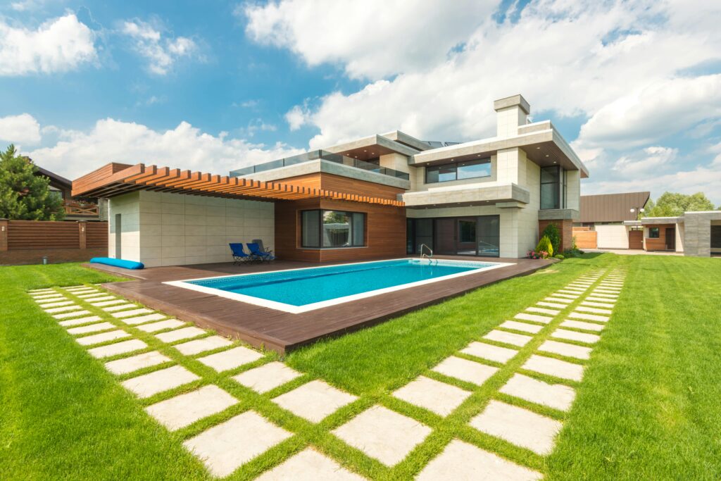 Contemporary house with pool, green lawn, and clear sky view.